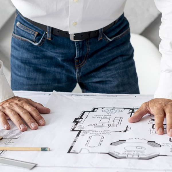 Person reviewing architectural blueprints on a table.